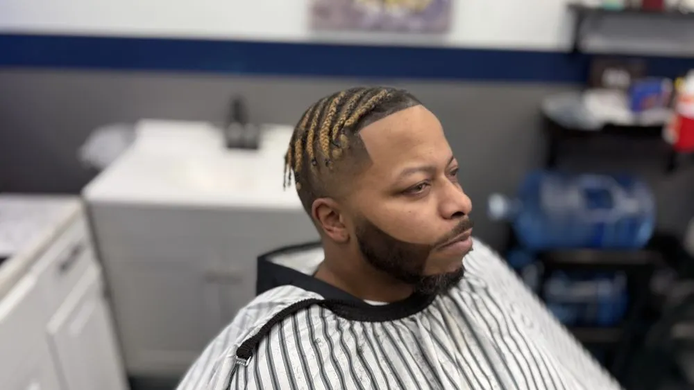 Braids with sharp lineup and beard shape at Parma barbershop.