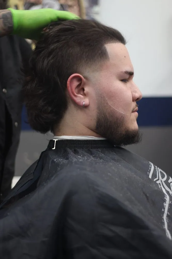 Barber working on a fade with precision clippers.