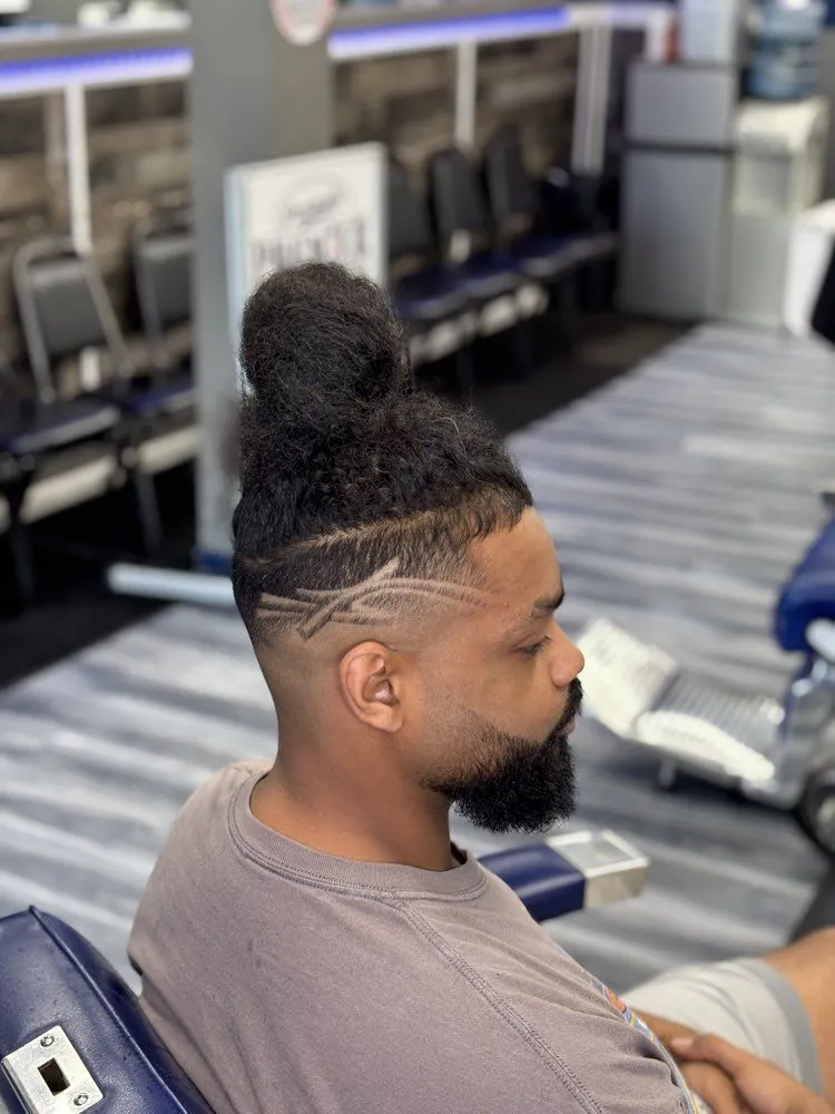 Man bun with design lines and skin fade.